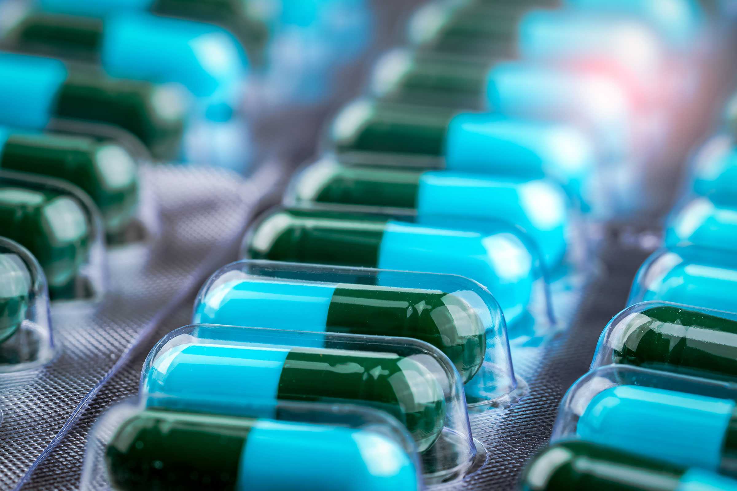 cirQum-beratung-qualityagreements Zweifarbige Hartgelatinekapseln (dunkelgrün und türkis) in Blisterverpackungen.