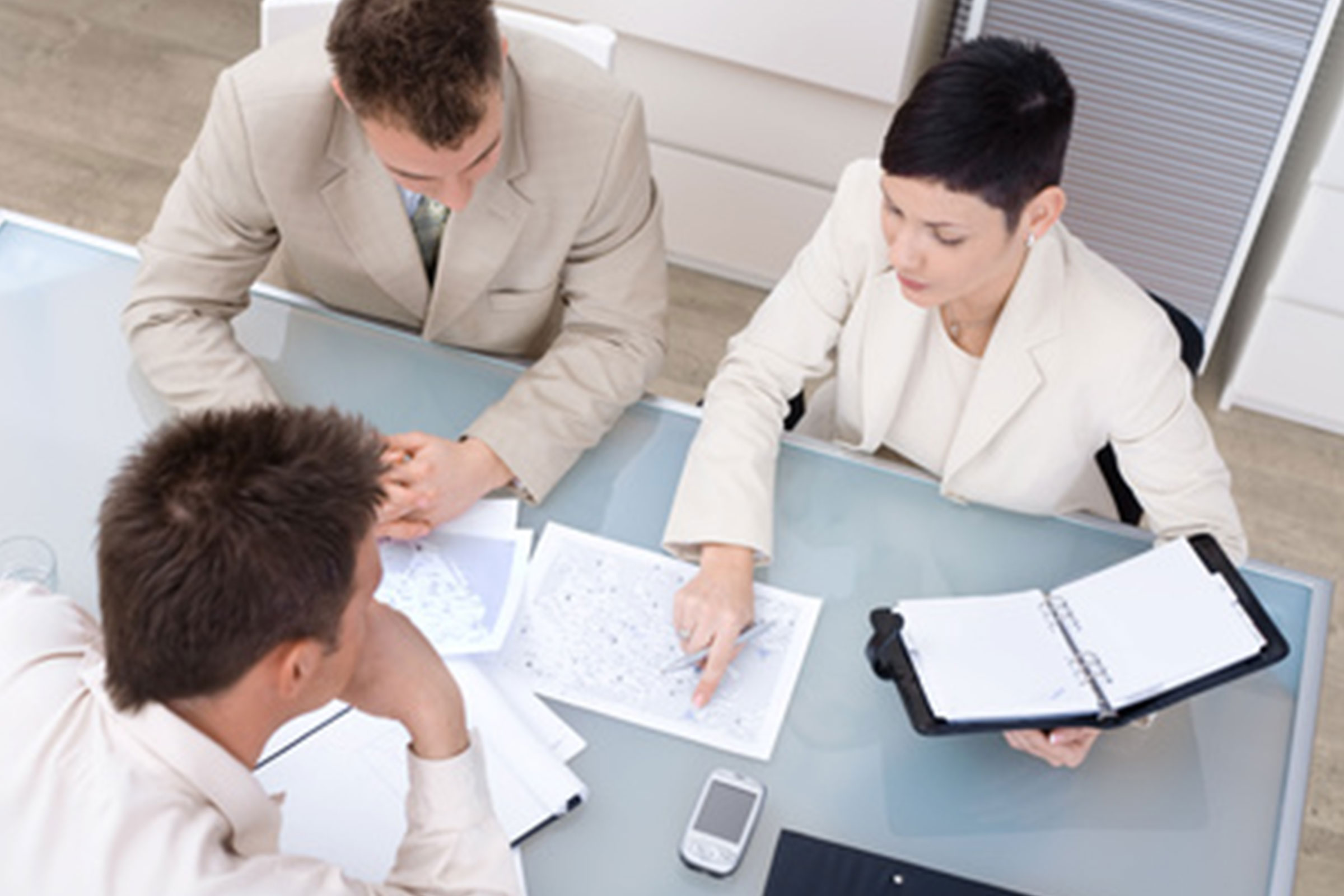 cirQum-cannabis-vermittler Drei Menschen sitzen während einer Besprechung an einem Tisch.