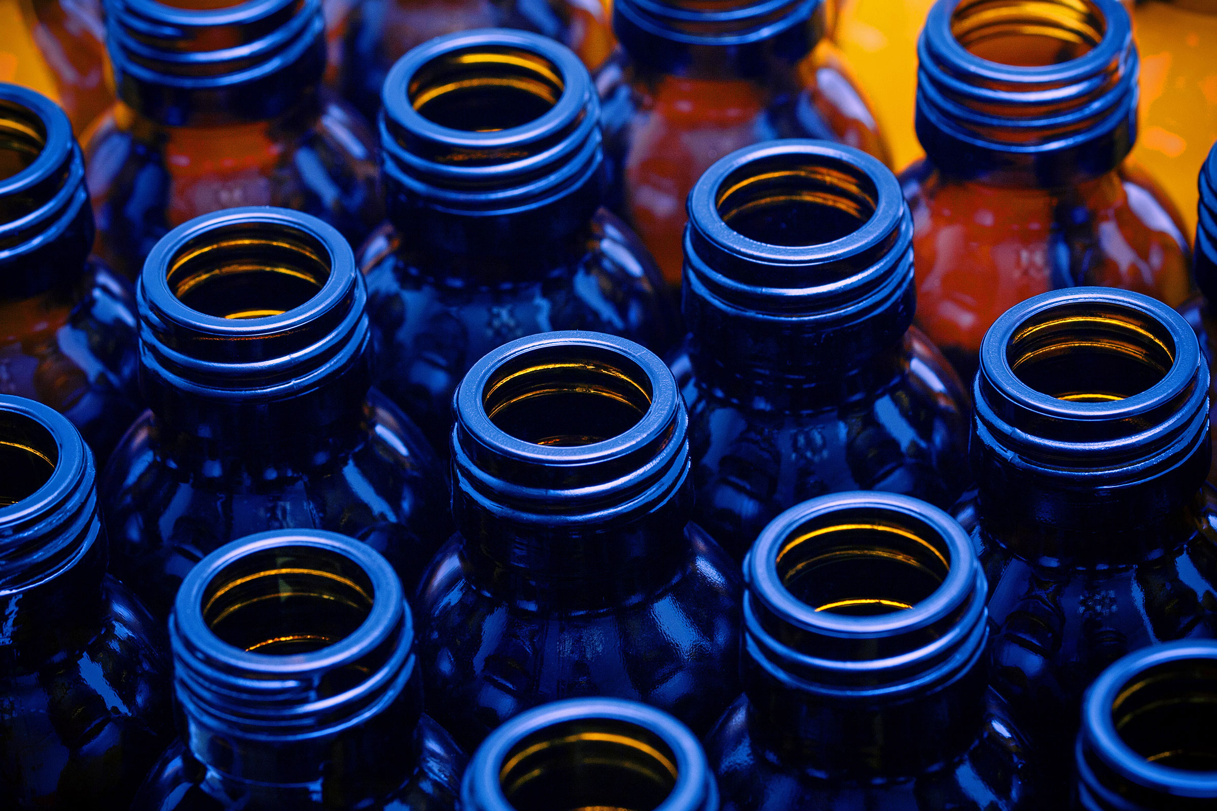 cirQum-schulungen-packmittel Blick von oben auf offene Braunglasflaschen in blauem Licht.